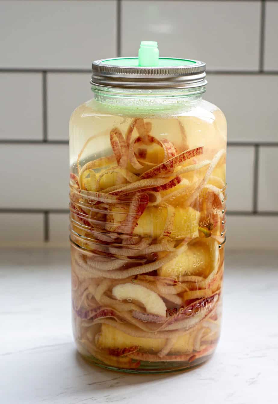 a large mason jar of apple peels and cores with an airlock