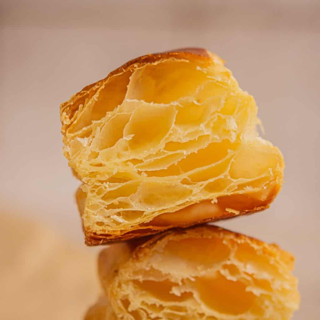 A close-up of a halved sourdough puff pastry made with sourdough puff pastry, showing its golden, flaky, and airy layers, highlighting the light and crispy texture of the pastry.