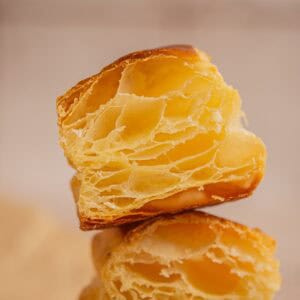 A close-up of a halved sourdough puff pastry made with sourdough puff pastry, showing its golden, flaky, and airy layers, highlighting the light and crispy texture of the pastry.