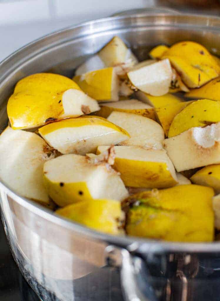 quince pieces simmering in water in a silver pot
