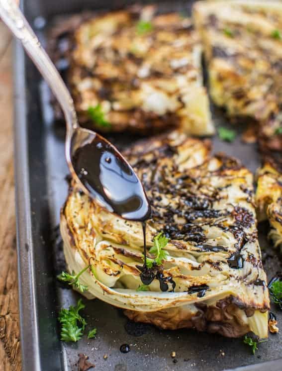 Roasted cabbage steaks drizzled with balsamic reduction, side view 