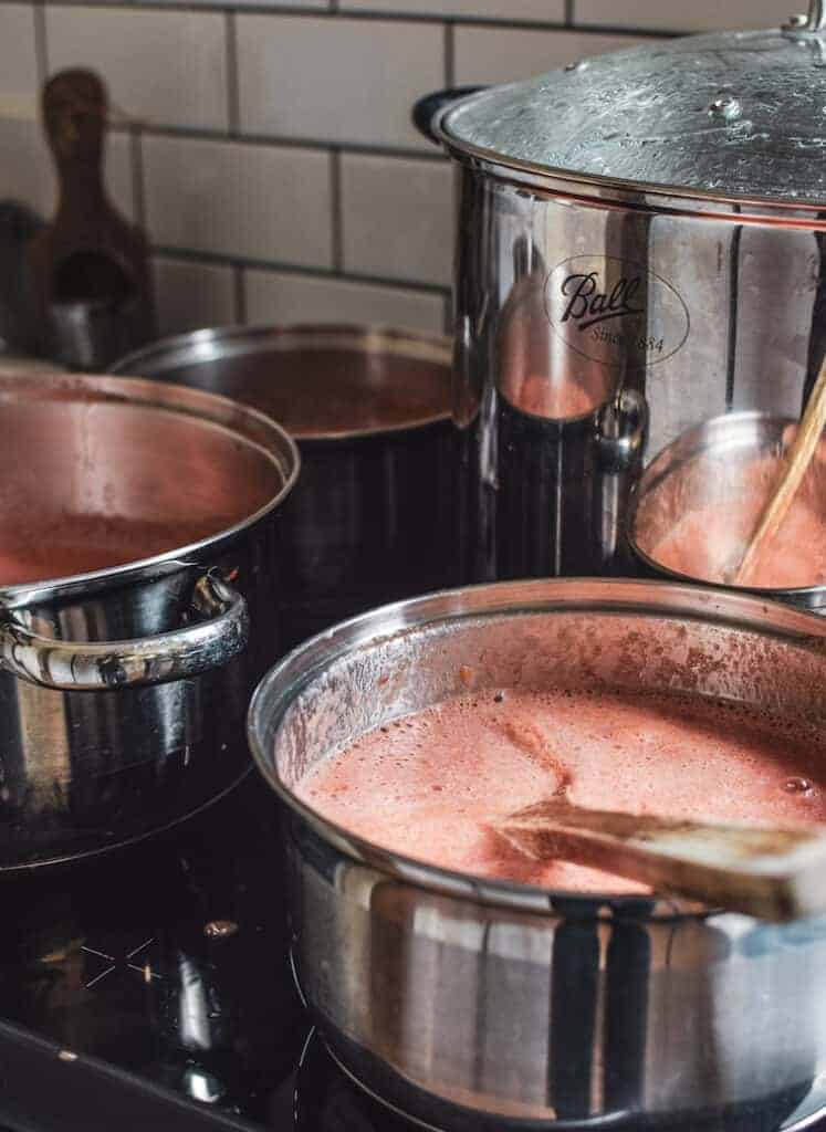 3 saucepans of passata being cooked on the stove 