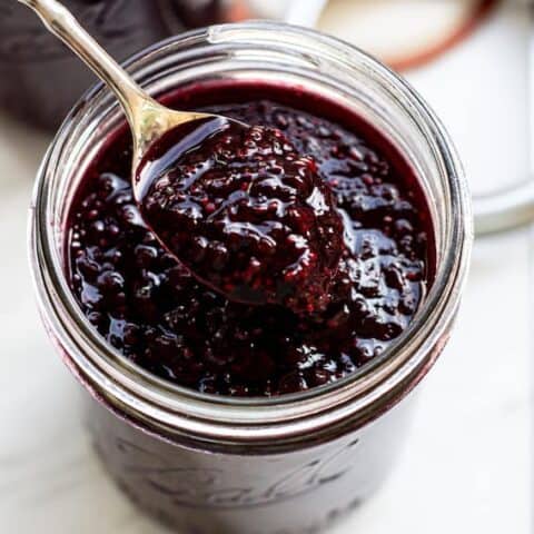 A jar of jam with a spoon in it scooping it out