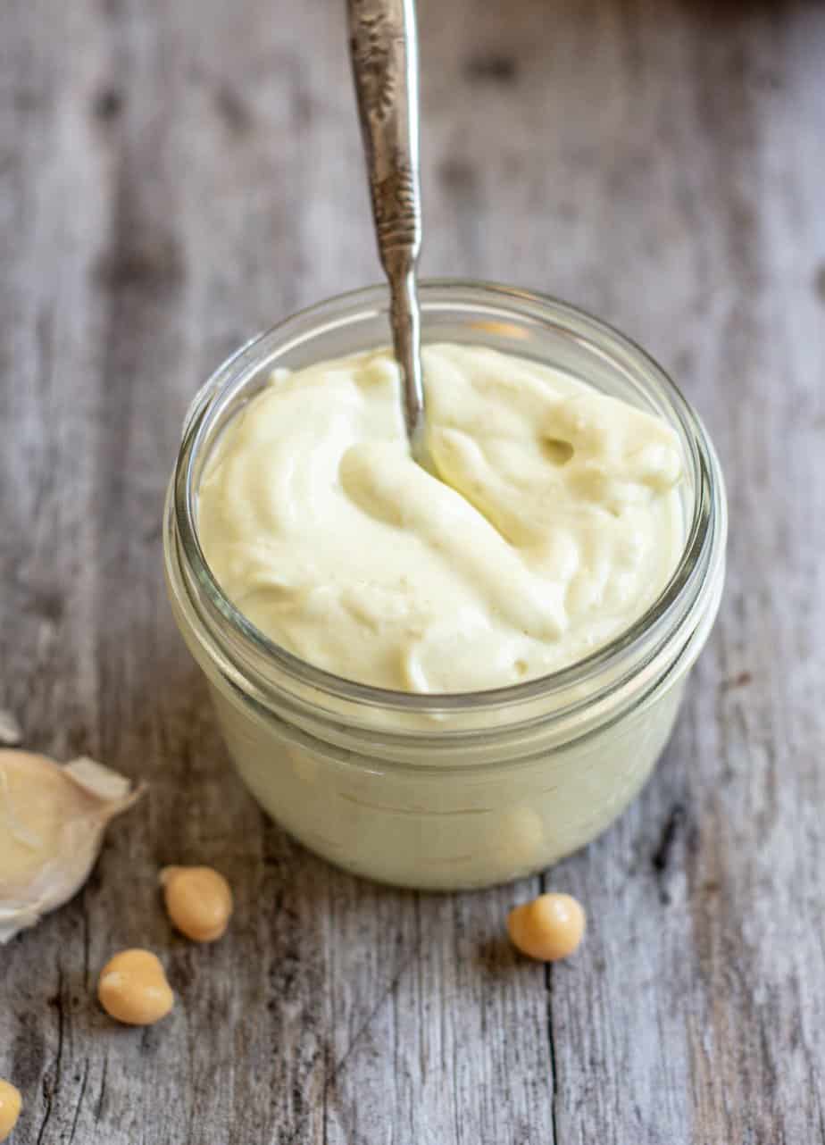 a pot of vegan mayo with chickpeas around it