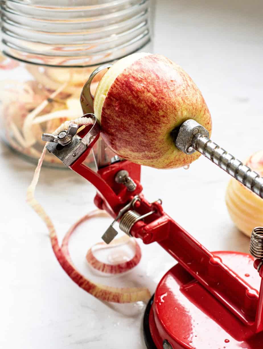 a red apple corer coring apples on a white bench