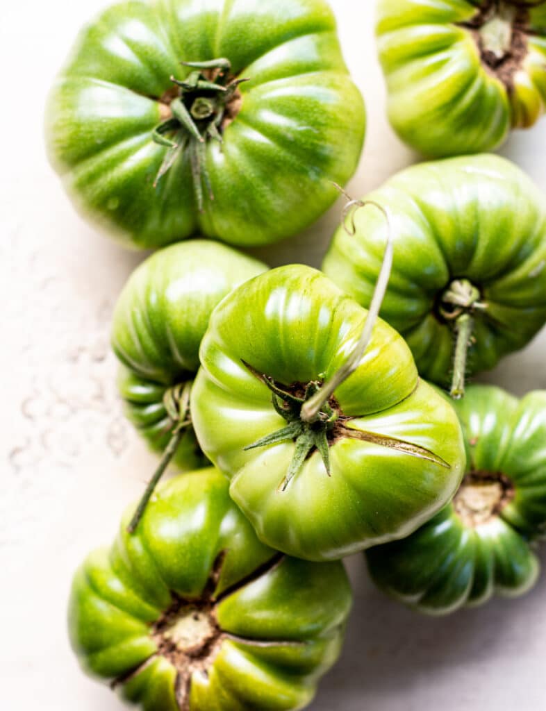 a stack of big green tomatoes on a white table