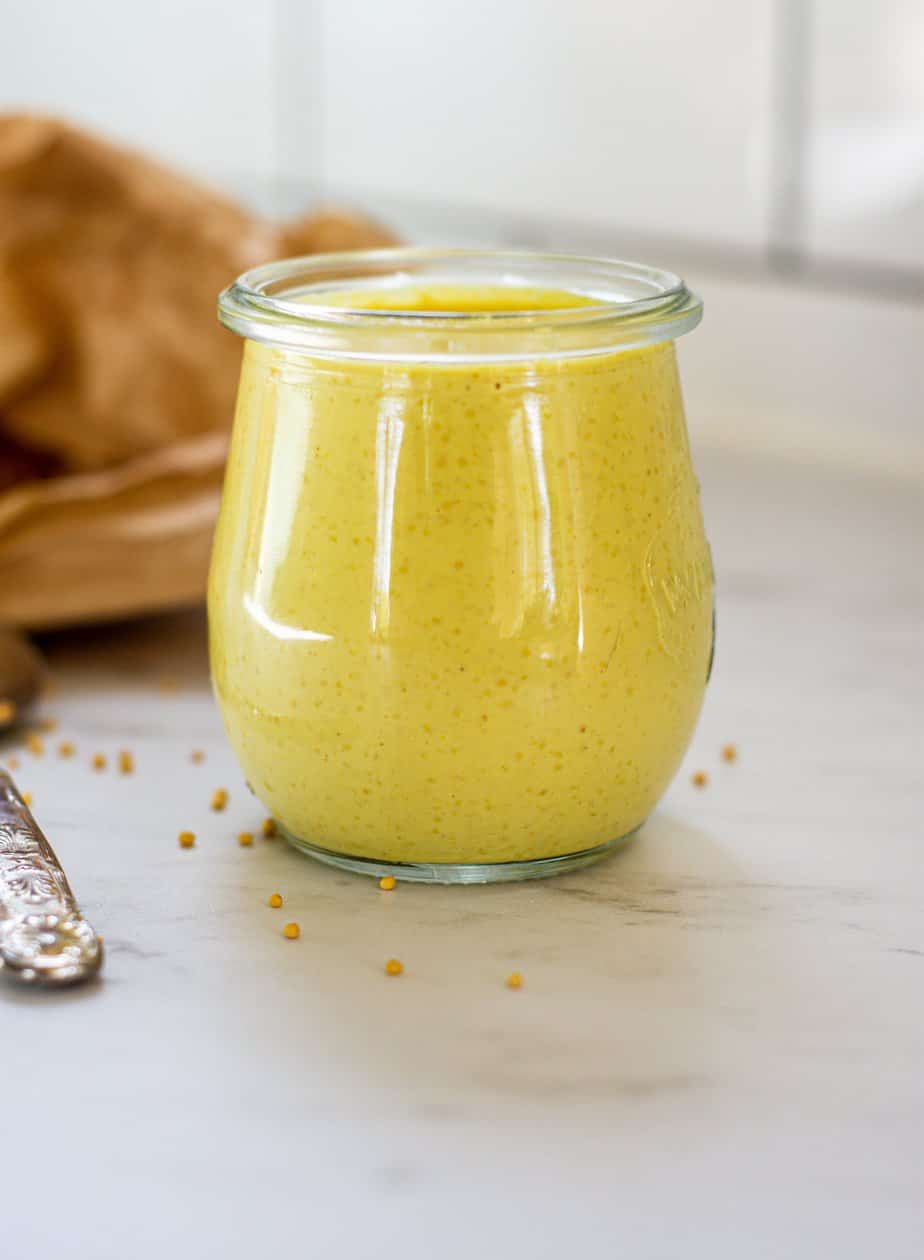 a jar of yellow mustard on a white bench