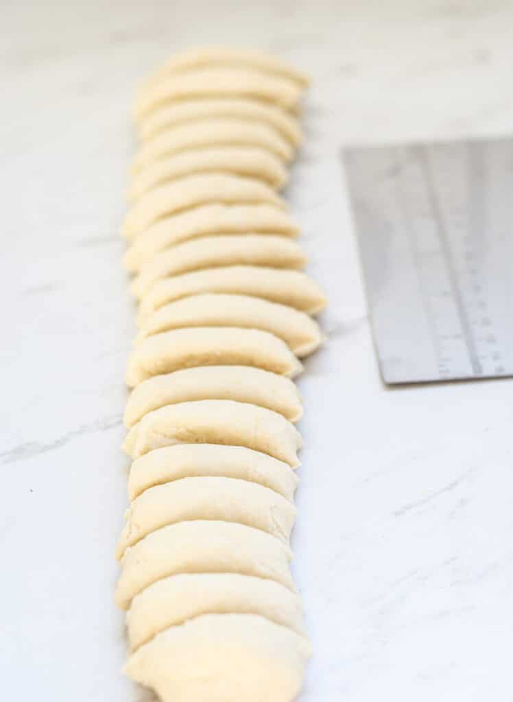 a length of dough being cut int pieces with a dough cutter