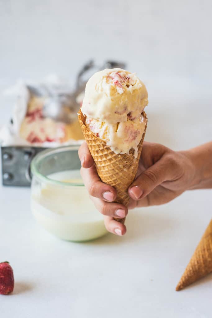a hand holding an ice cream with two scoops.