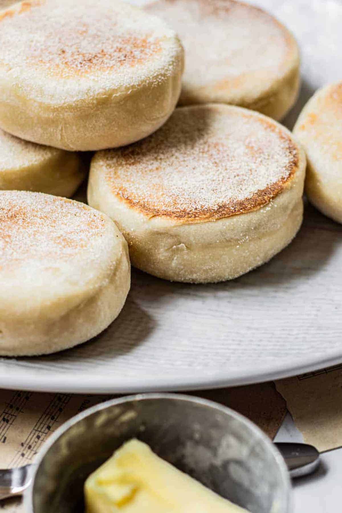 high angled view of stacked English muffins with butter in forefront.