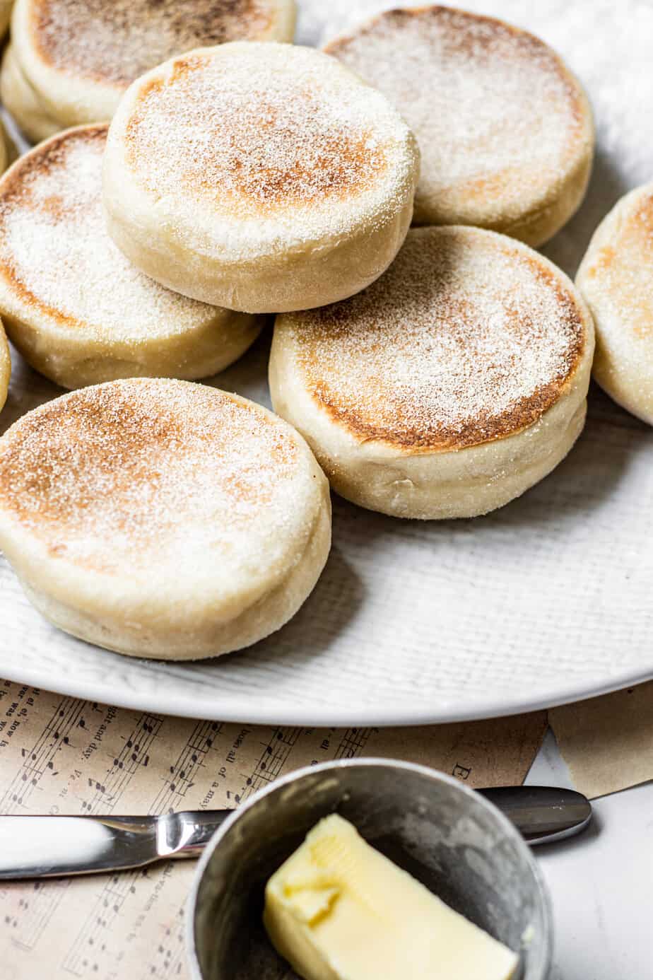 high angled view of stacked English muffins with butter in forefront.