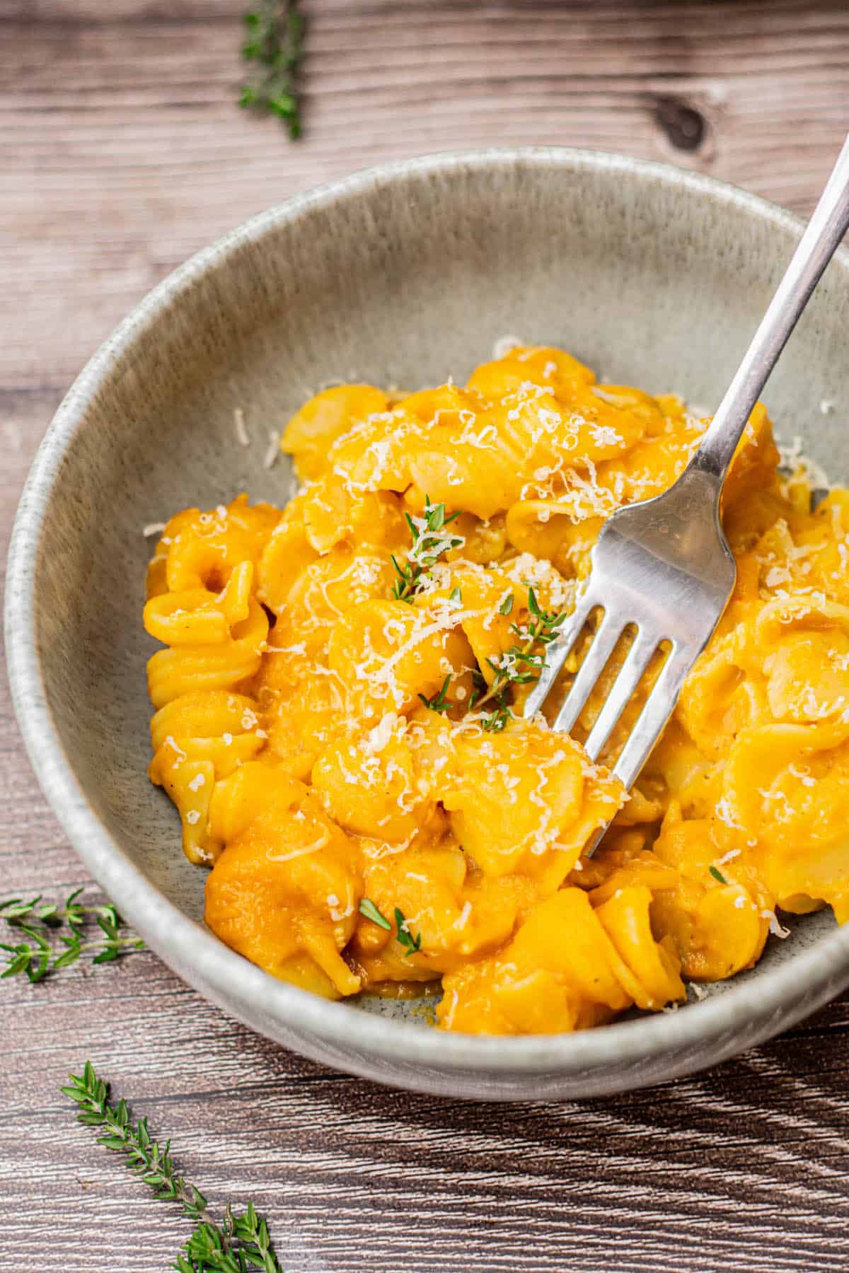 A fork in a bowl of orange pasta.