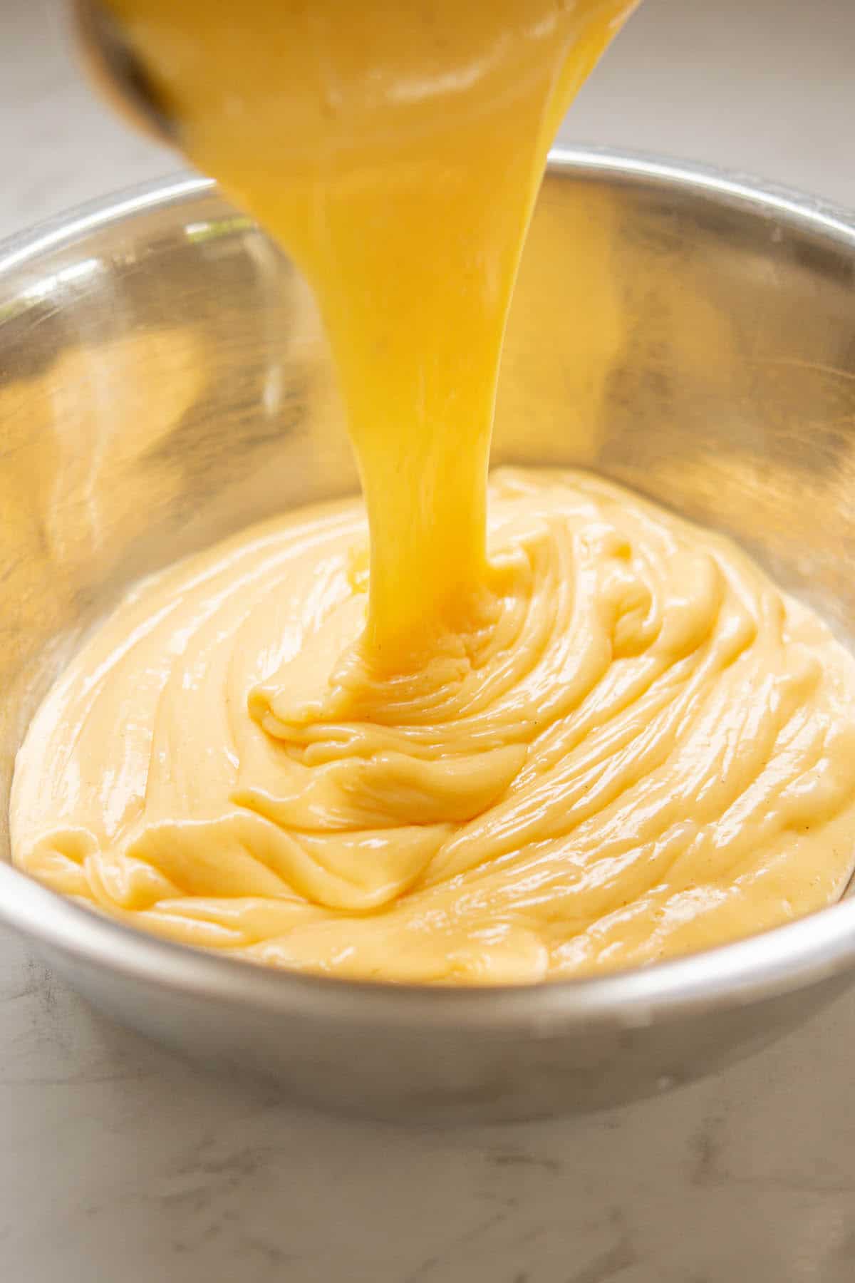 pastry cream being poured into a bowl.