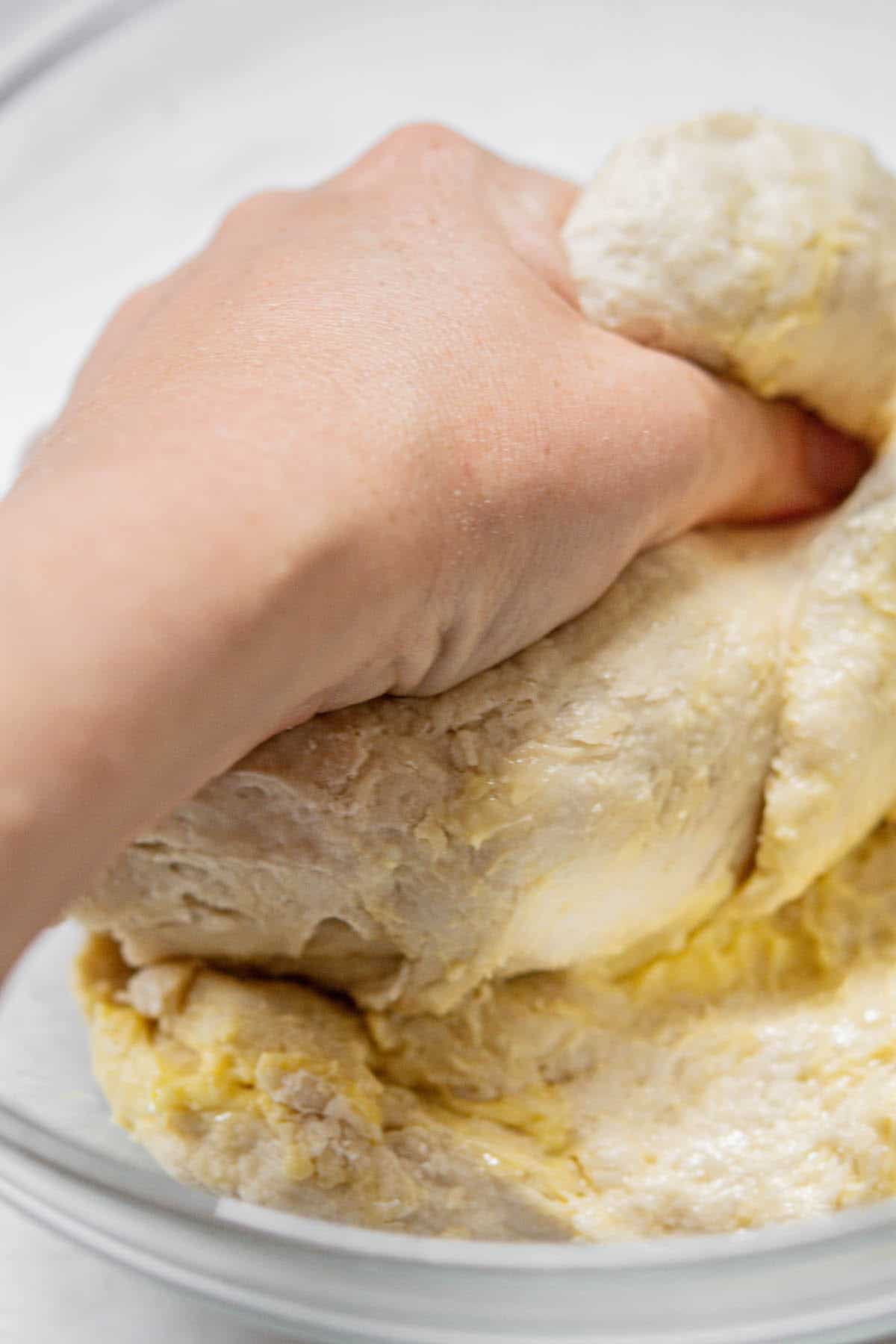 hand kneading butter into dough.