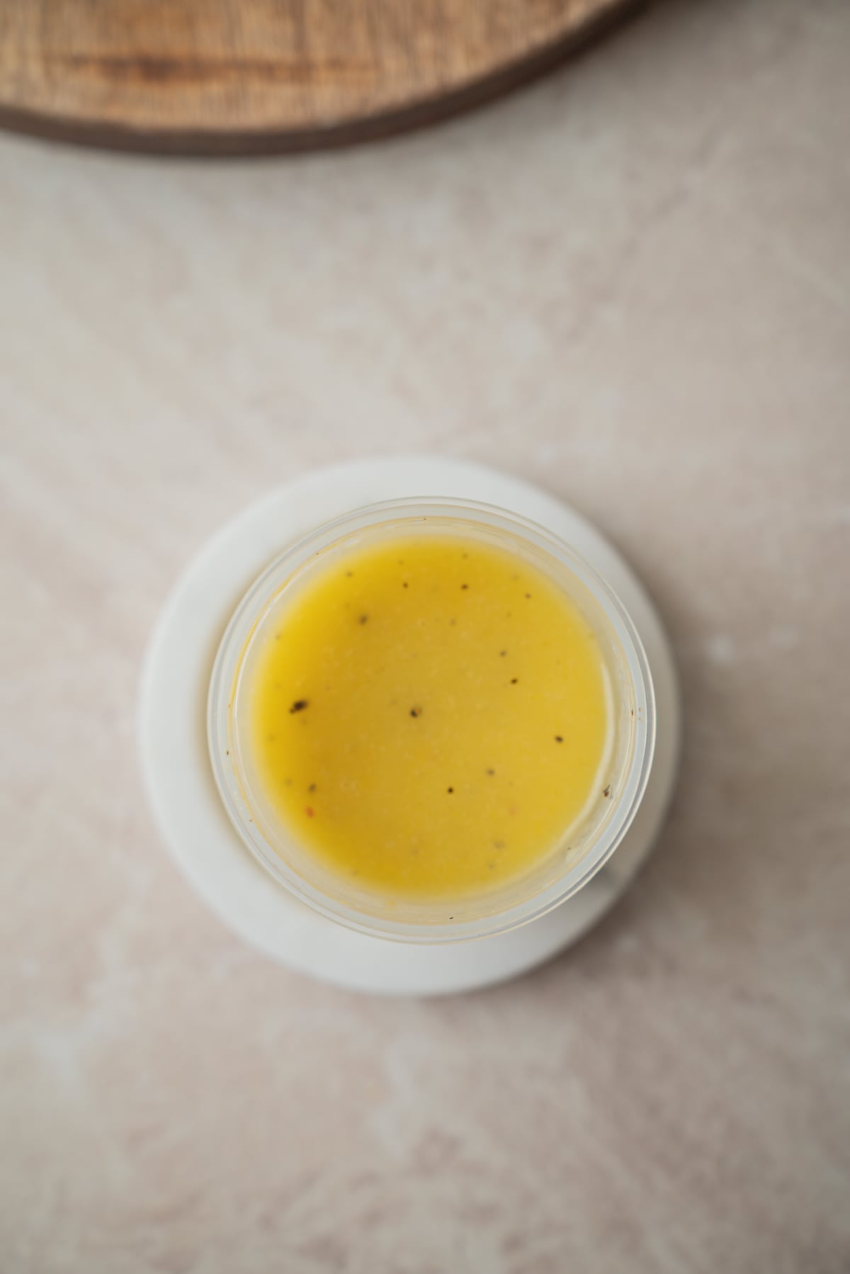 A small glass container filled with yellow salad dressing, viewed from directly above.